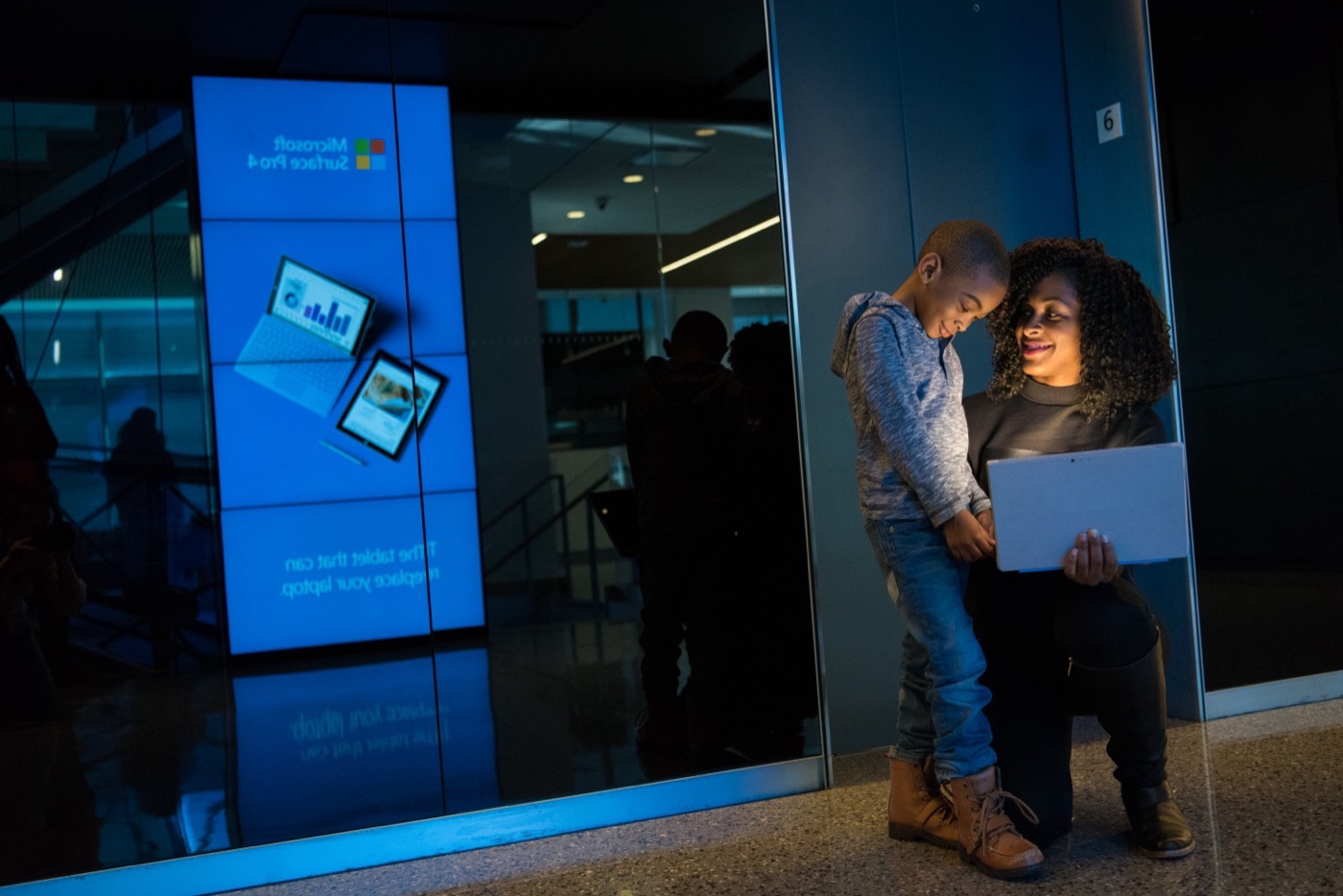 A woman with natural curls shares a tablet with a child.