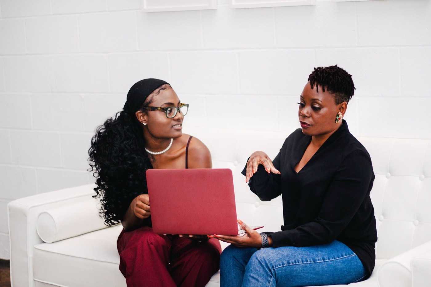 Two women working through a laptop together.
