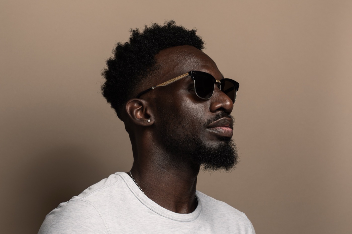 Profile portrait of a man with a beard and natural hair.